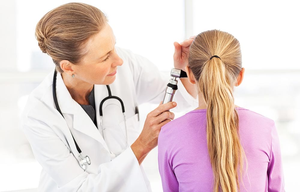 Doctor checking child’s ear for earwax buildup to see if they need ear irrigation Doctor checking child’s ear for earwax buildup to see if they need ear irrigation